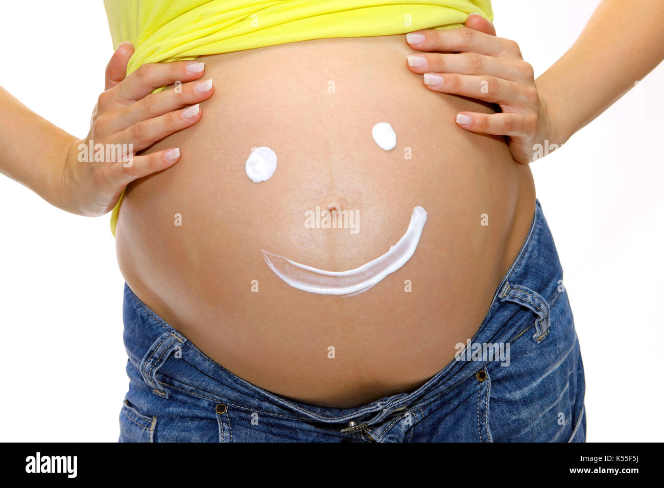 Pregnant woman with painted smiley face on her  baby belly Stock Photo