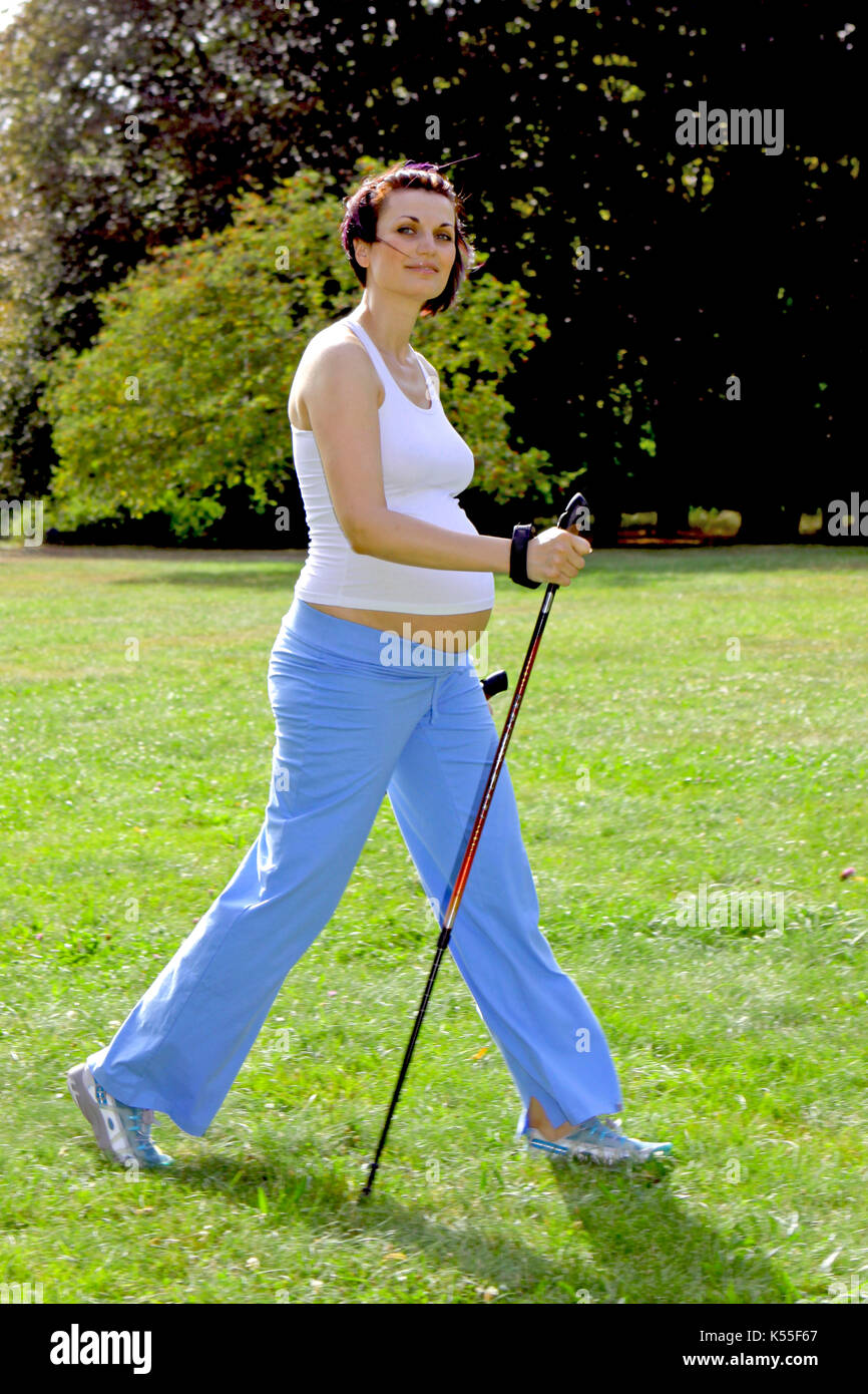 Pregnant woman in summer doing Nordic walking Stock Photo