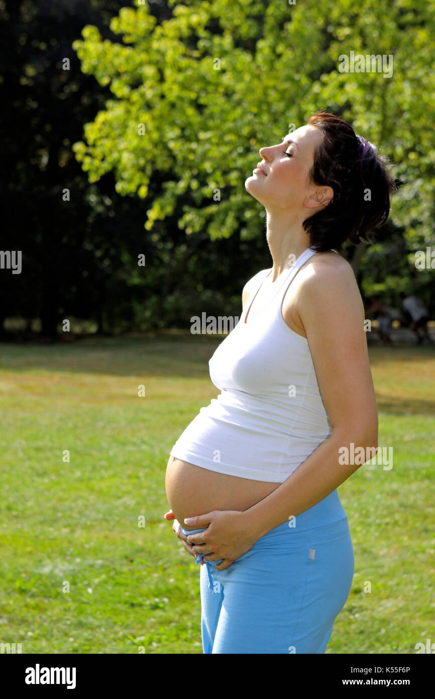 Happy pregnant woman relax in a park in summer Stock Photo
