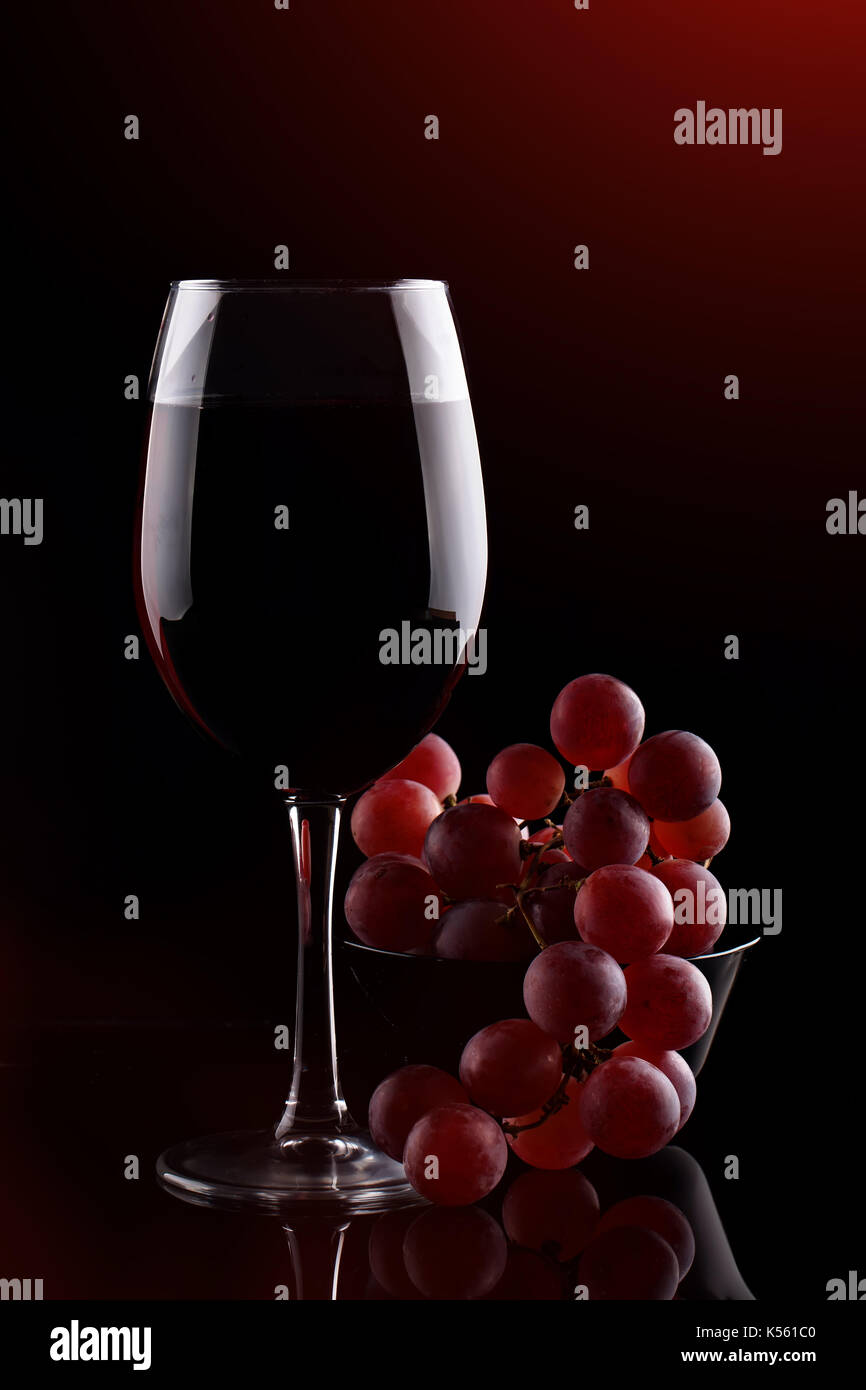 https://c8.alamy.com/comp/K561C0/a-glass-of-red-wine-and-red-grapes-on-a-dark-background-K561C0.jpg