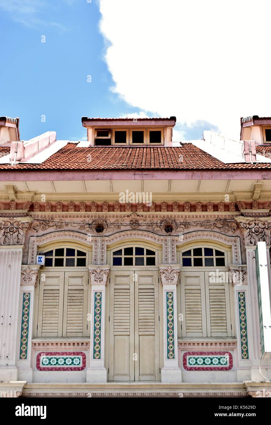 Row of three traditional shop house exteriors with white wooden louvered shutters and arched windows in the Joo Chiat  District of Singapore Stock Photo