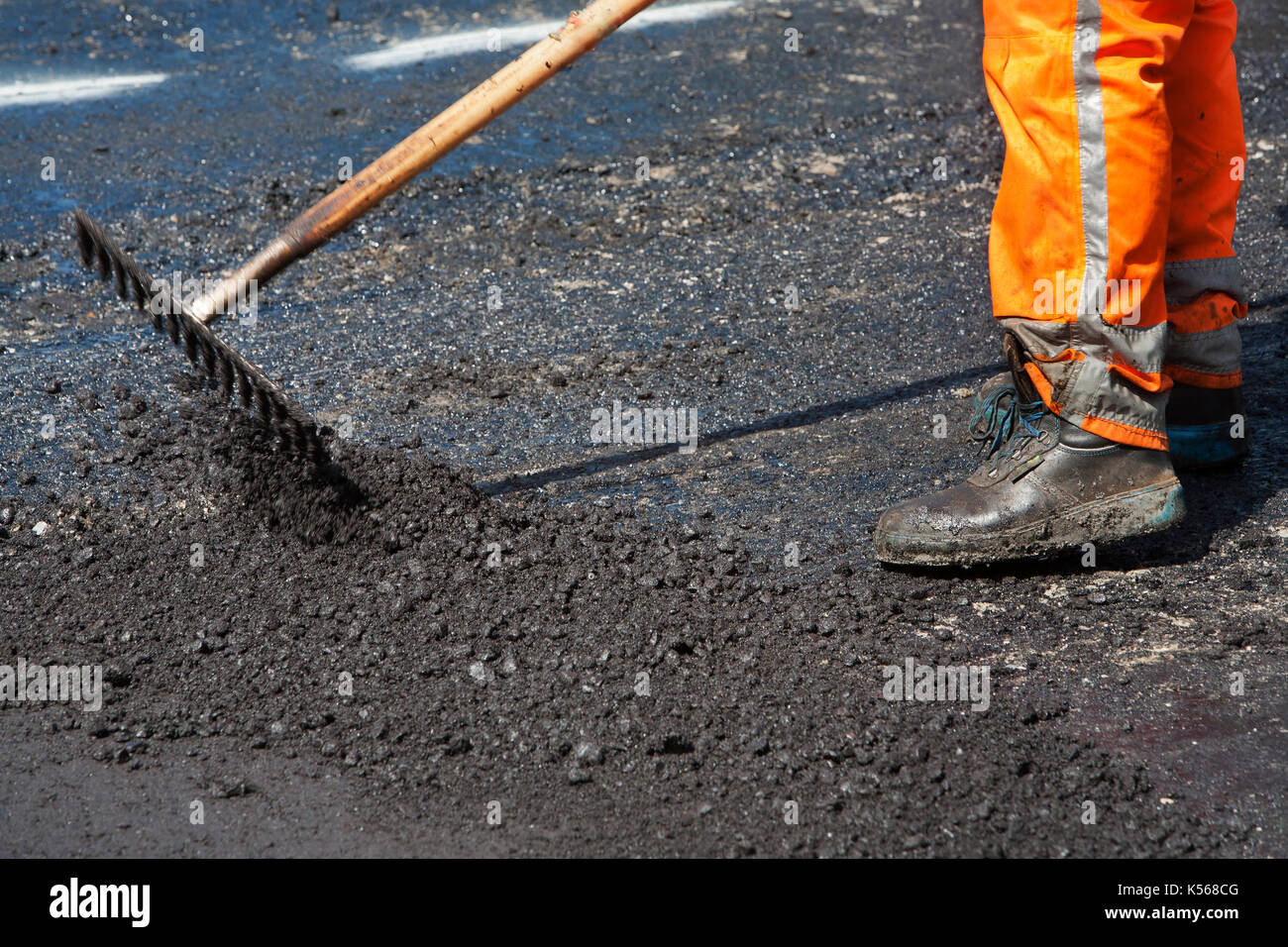 Manual worker leveling asphalt with a rake Stock Photo