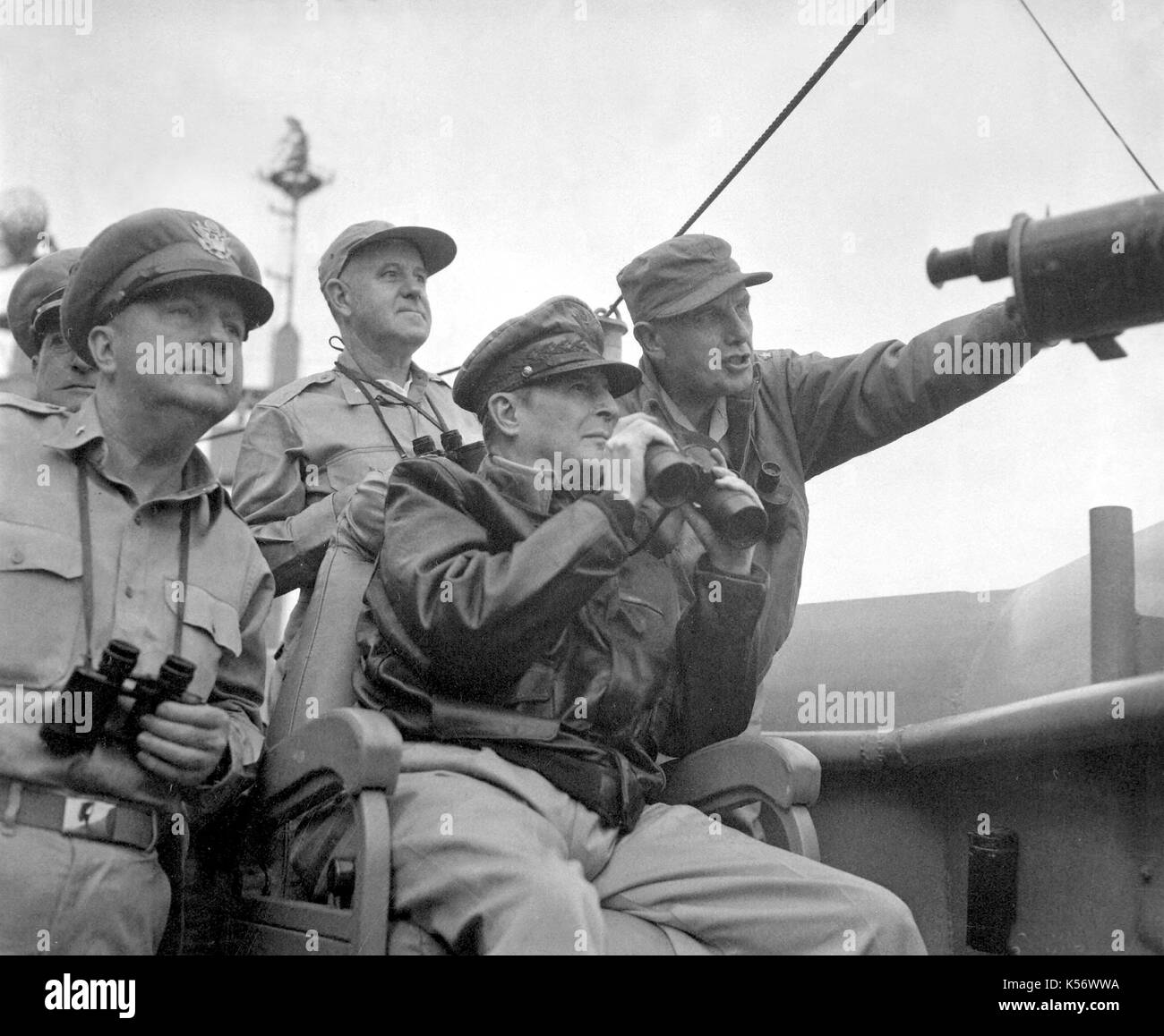 Brigadier General Courtney Whitney, government section, Far East Command; General Douglas MacArthur, Commander-in-Chief, United Nations Command, and Major General Edward Almond (at right, pointing), Commanding General, X Corps in Korea, observe the shelling of Incheon from the USS Mount McKinley. Stock Photo
