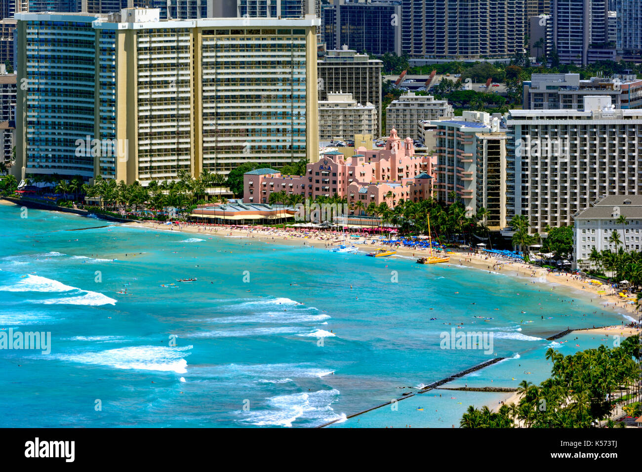 Waikiki beach with coastline and hotels in the background. Pink building, hotels, catamaran sailboats, swimmers and surfers Stock Photo
