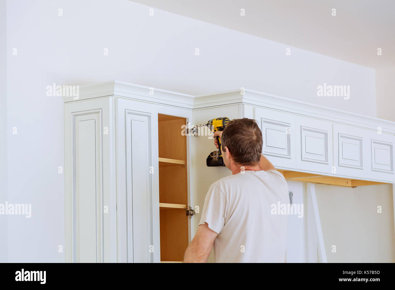 technician-man-installing-kitchen-cabinets-installation-of-kitchen-K57B5D.jpg