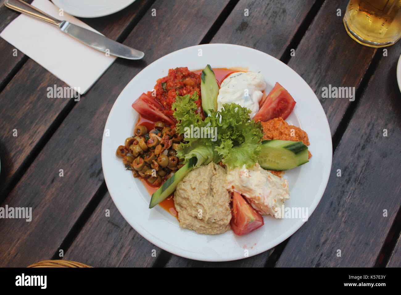 Turkish Sharing Platter with Dips Including Hummus, Chilli, Carrot, Tomato and Tzatziki Served with Greens. Stock Photo