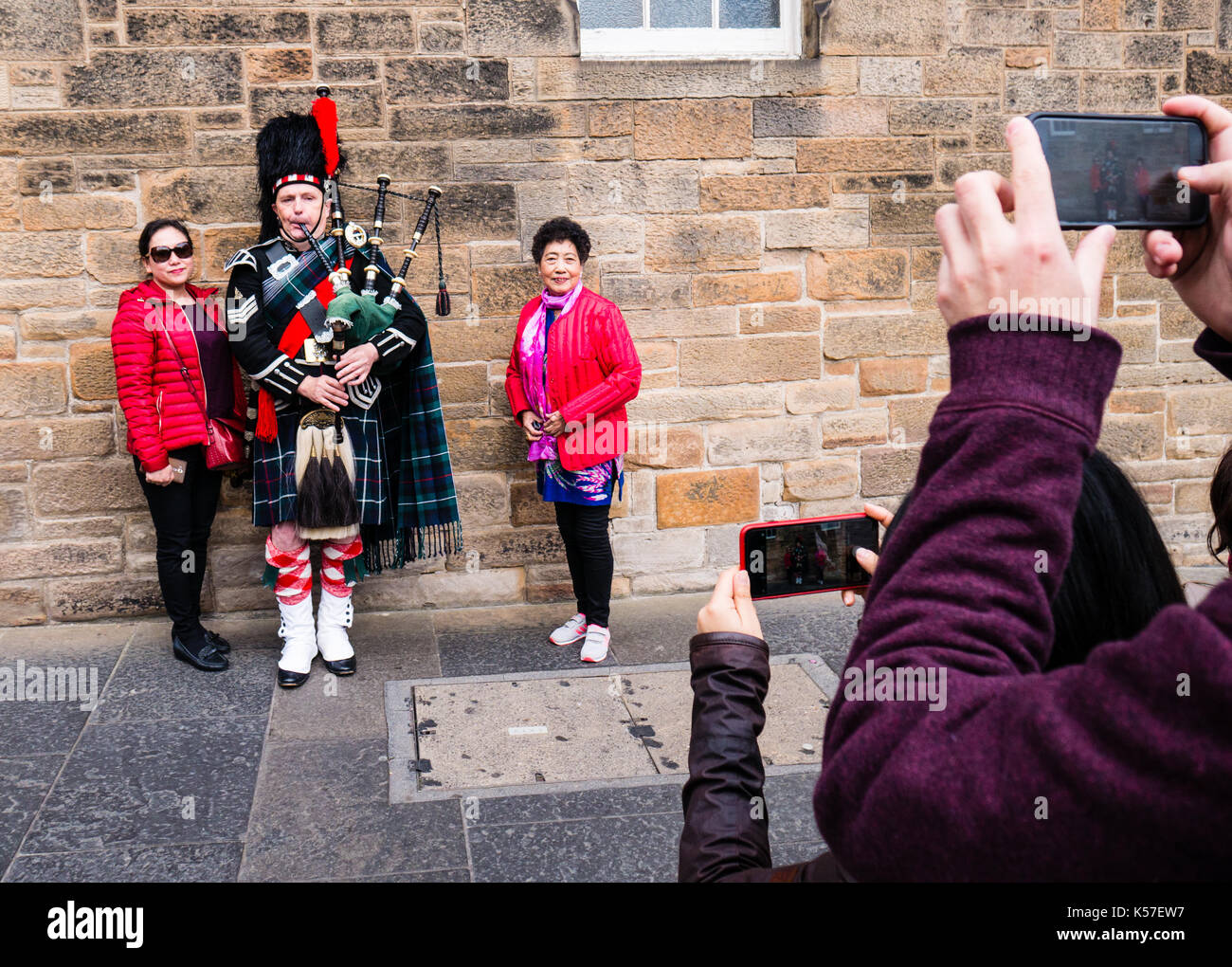 Chinese Tourists with Scottish bagpipe Player, The Royal Mile, Old Town, Edinburgh, Scotland, UK, GB. Stock Photo