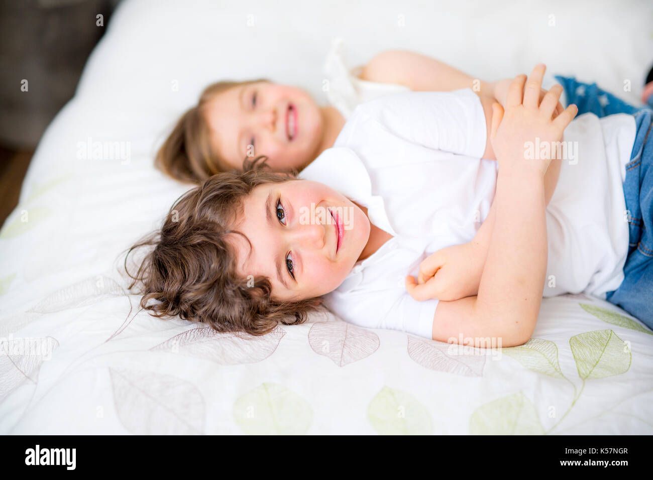 Brother And Sister Relaxing Together In Bed Stock Photo