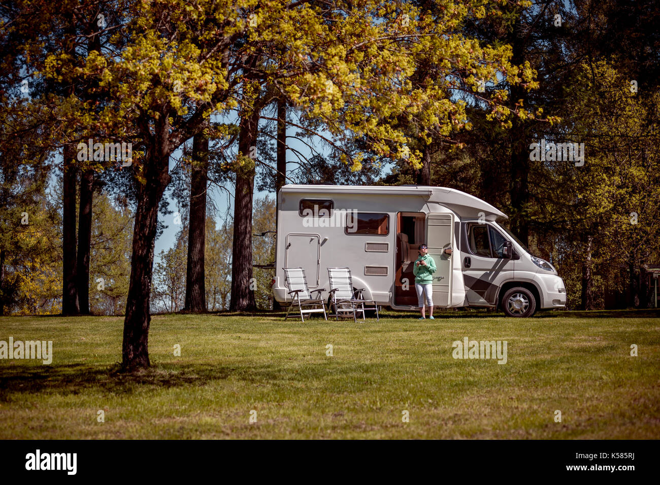 Woman is standing with a mug of coffee near the camper. Caravan car Vacation. Family vacation travel, holiday trip in motorhome Stock Photo