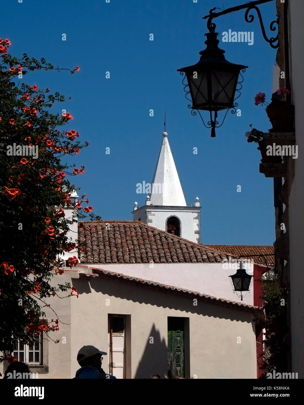 A white church spire is contrasted againts the sky in the walled medieval town of Obidos, in Portugal August 24, 2017. © John Voos Stock Photo