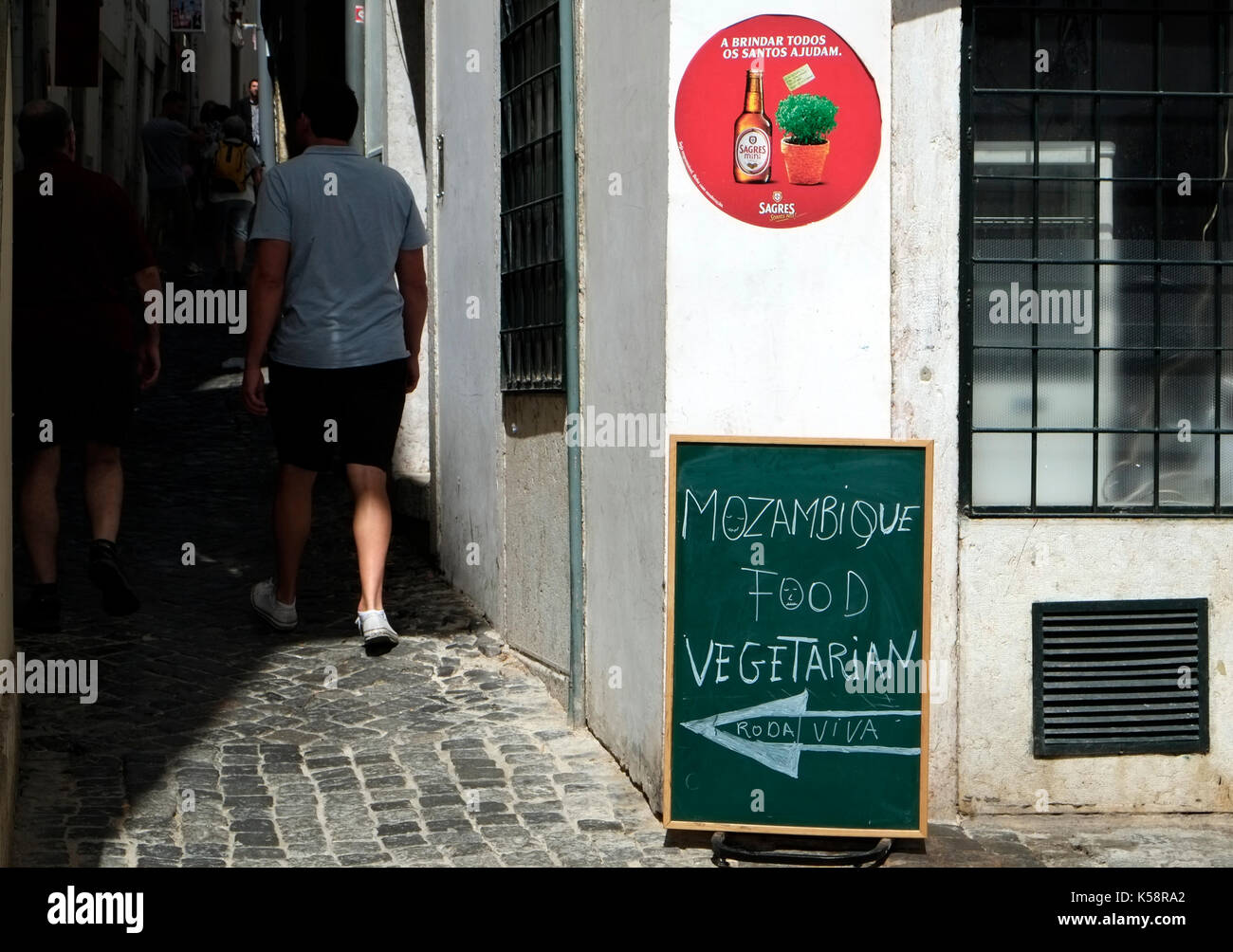 A tourist walks past a blackboard menu advertising Mozambique food in the old quarter of Lisbon, in Portugal August 26, 2017.  © John Voos Stock Photo