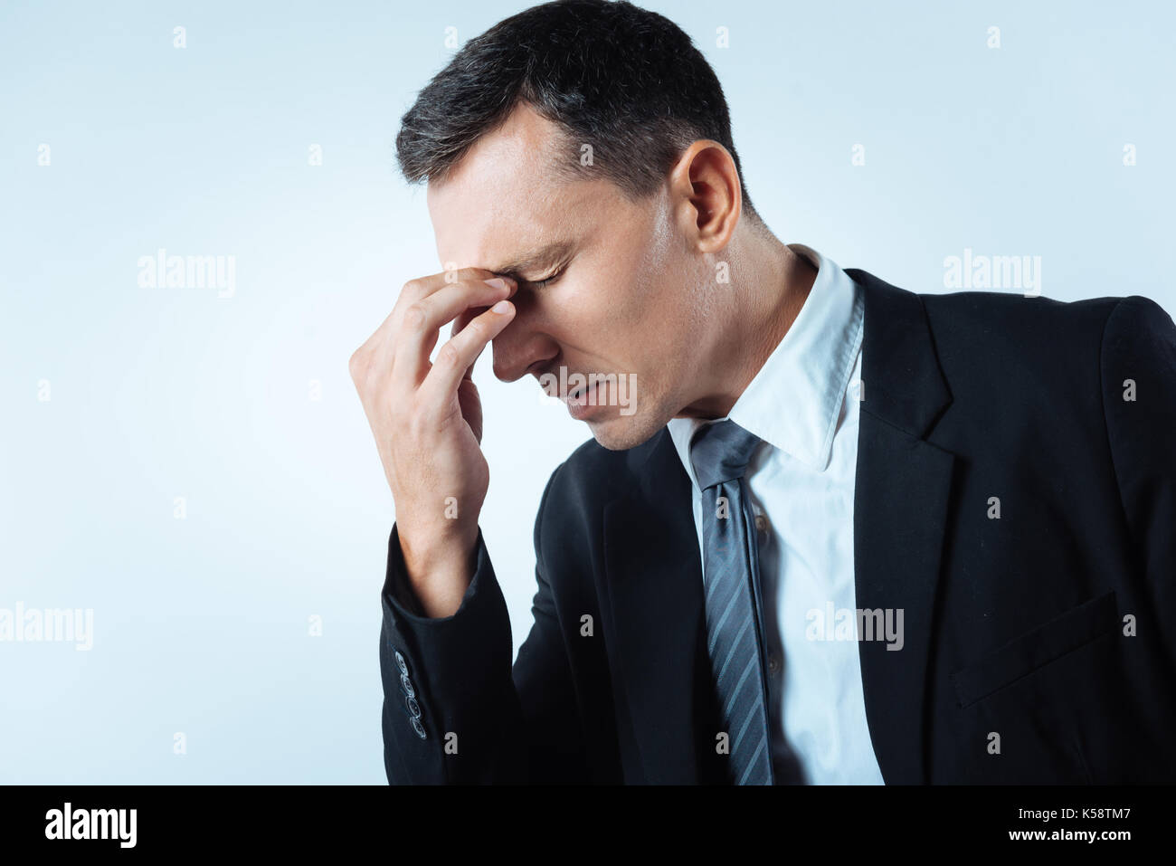 Nice Cheerless Man Holding Bridge Of His Nose Stock Photo - Alamy