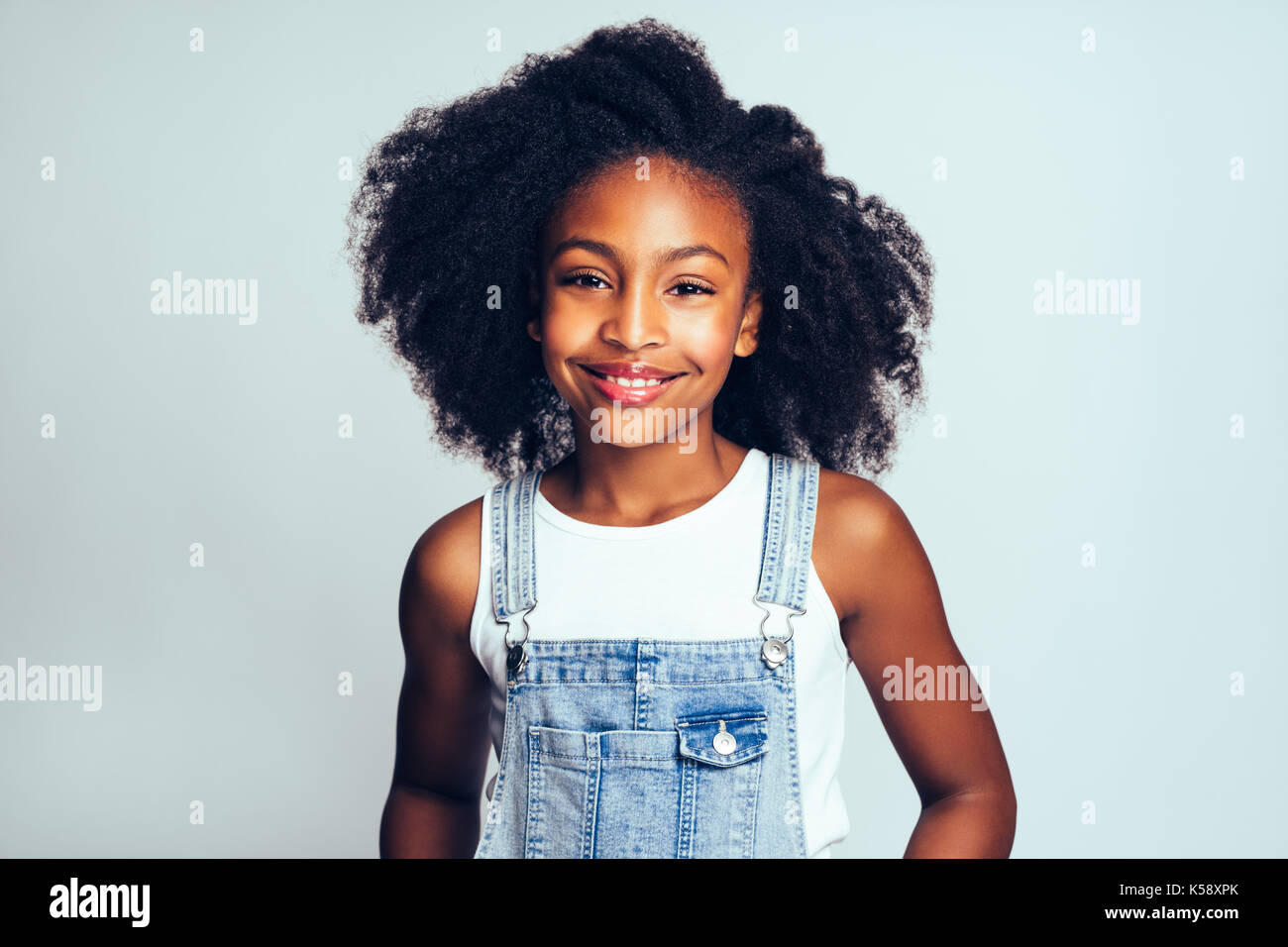Smiling little African girl with long curly hair smiling and wearing ...