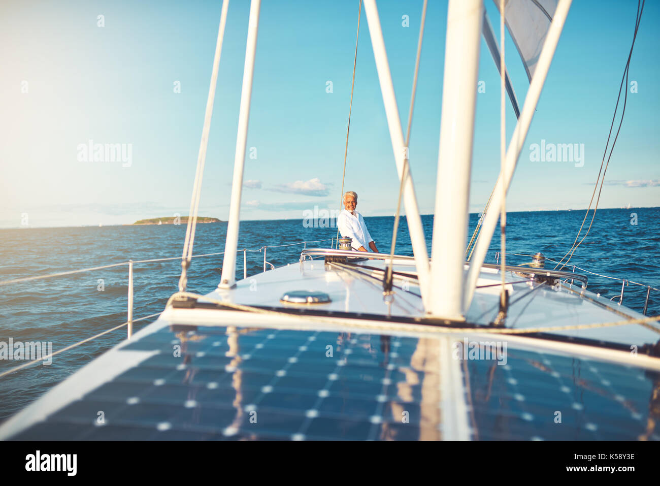 Mature man standing on the rear deck of his boat while out for a sail ...