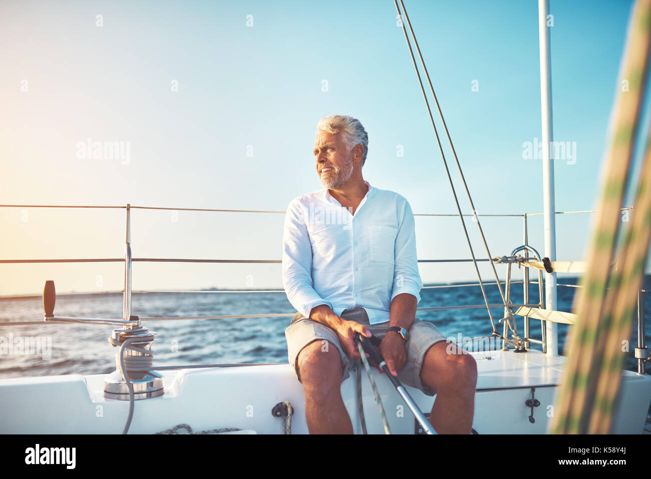 Mature man sitting on the deck of his yacht enjoying the day sailing on ...