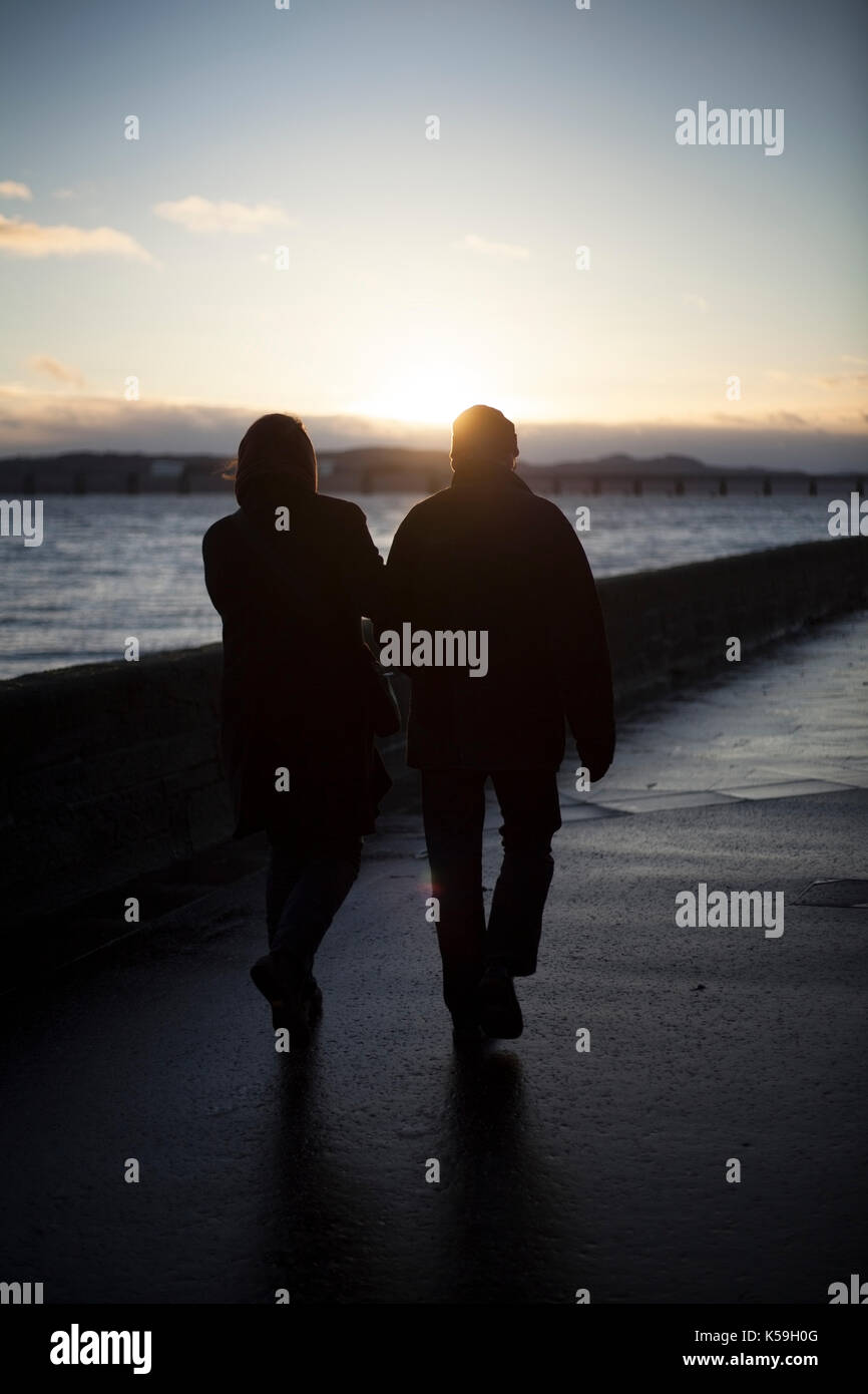 Couple holding hands, walking beside the River Tay, Broughty Ferry, Dundee, Scotland Stock Photo