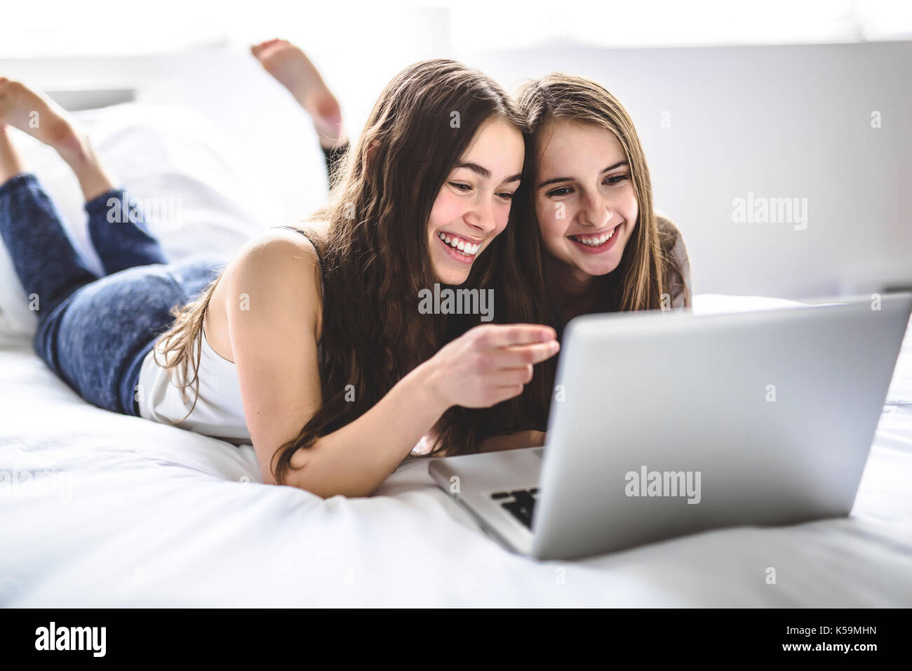 Teen Girls Lying On Bed Using A Laptop Stock Photo