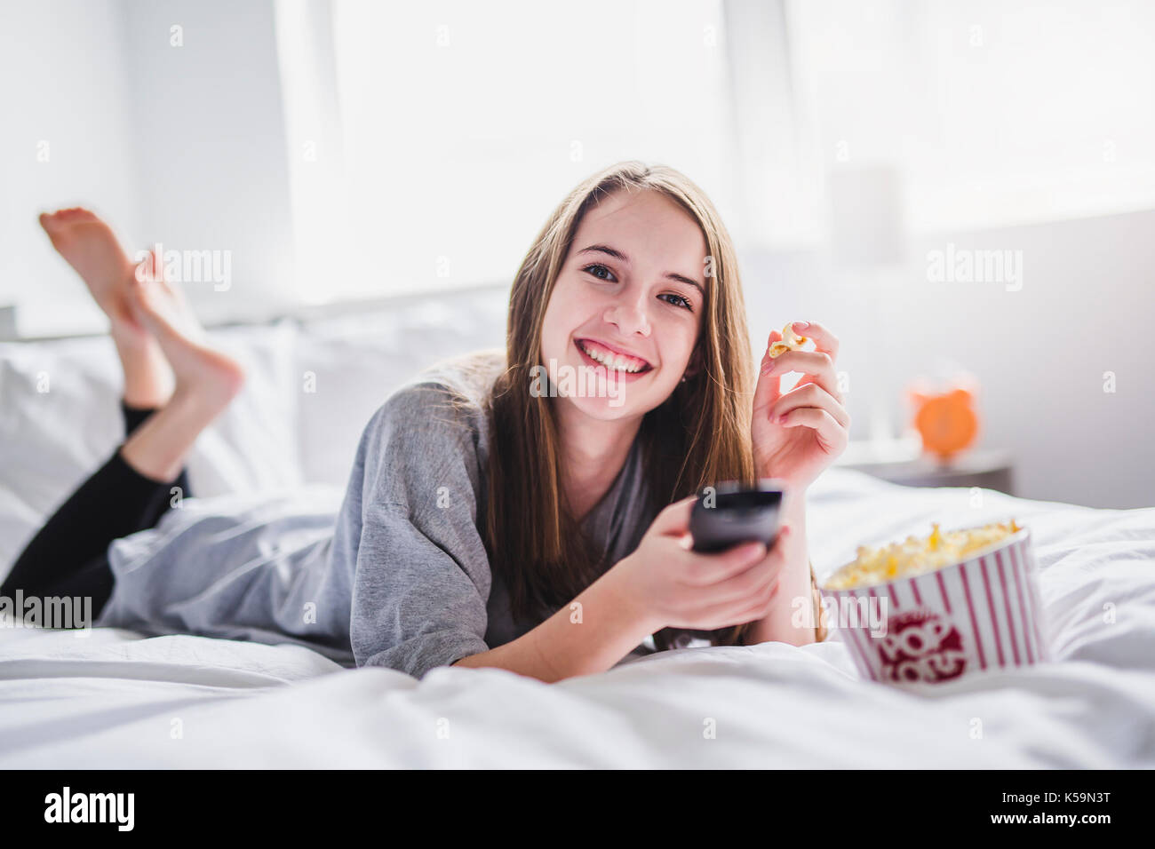 young teenager watching movies in bed with popcorn Stock Photo Alamy