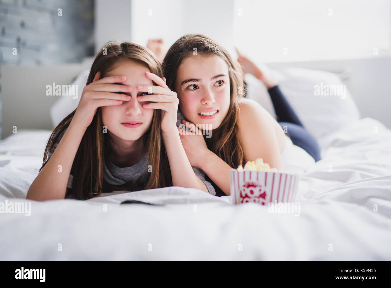 teenage girls eating popcorn and watching horror movie on tv at home Stock Photo