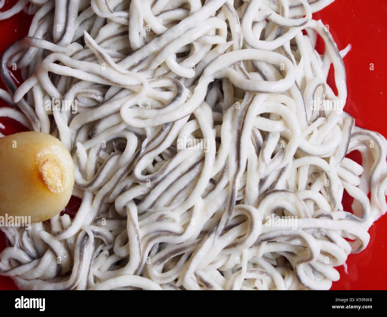 Baby eels with garlic on red plate Stock Photo Alamy