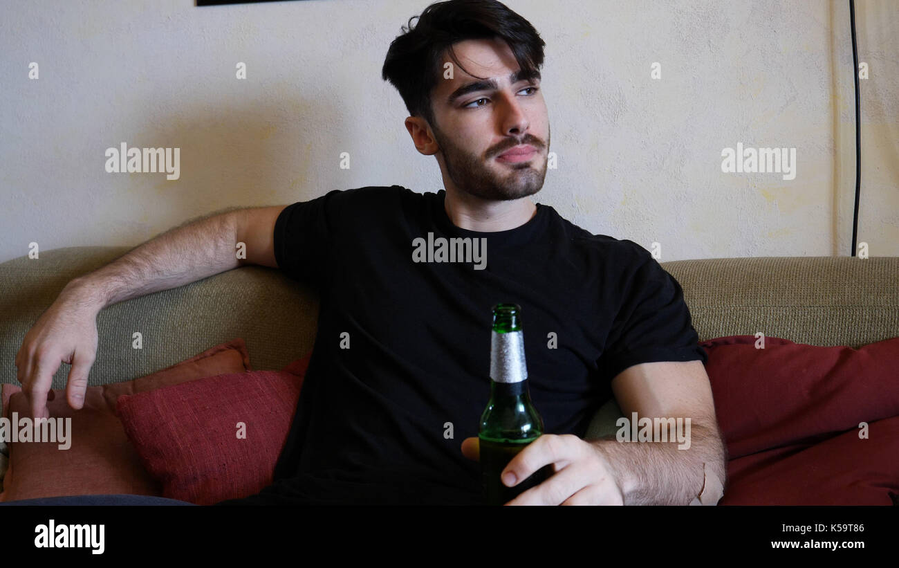 Young man on couch drinking beer Stock Photo Alamy
