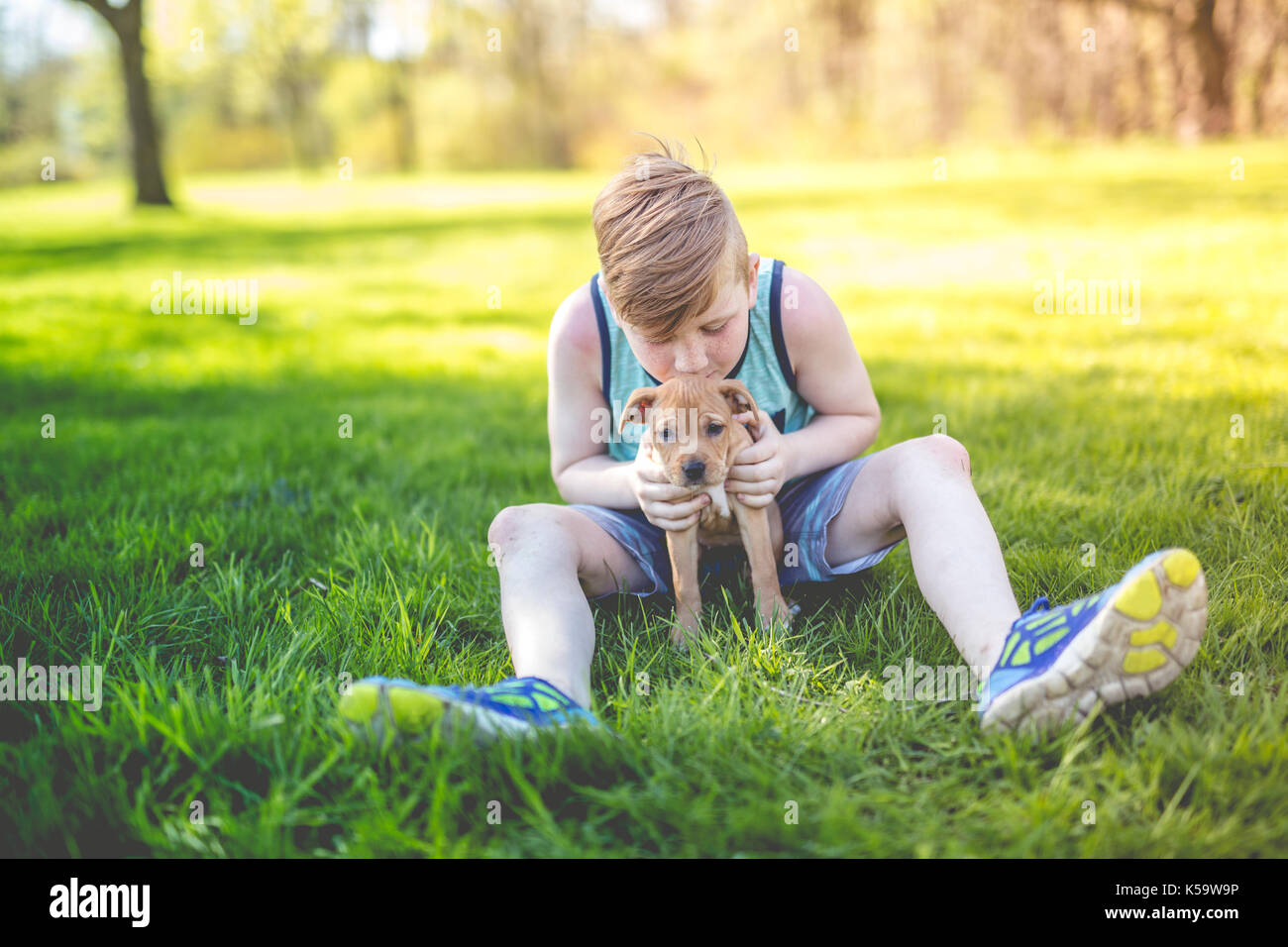 Cute, young boy in the garden holding a boxer dog Stock Photo