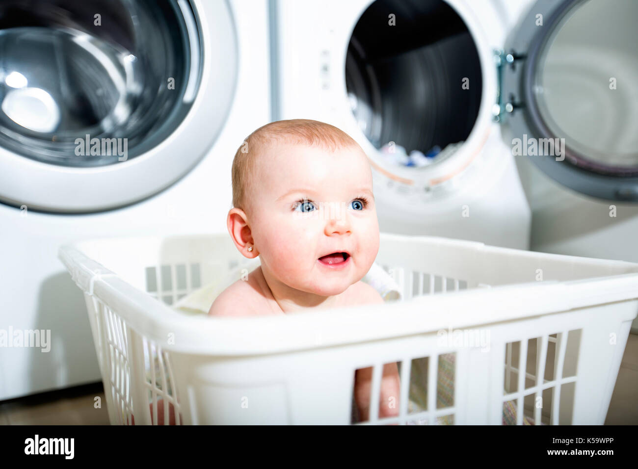 Portrait of an adorable baby sitting in a laundry basket Stock Photo