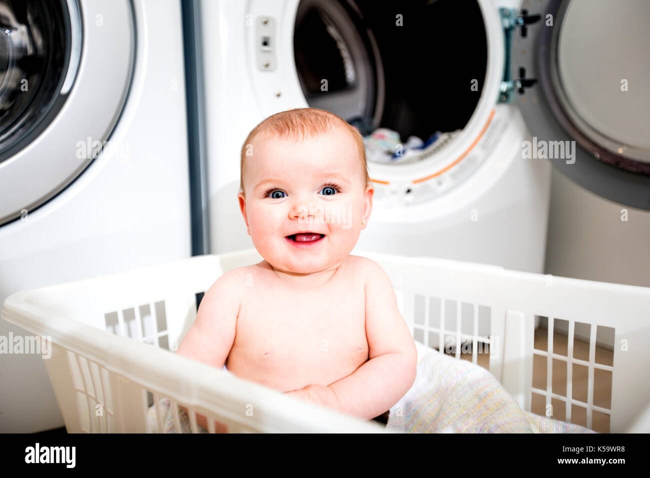 Portrait of an adorable baby sitting in a laundry basket Stock Photo