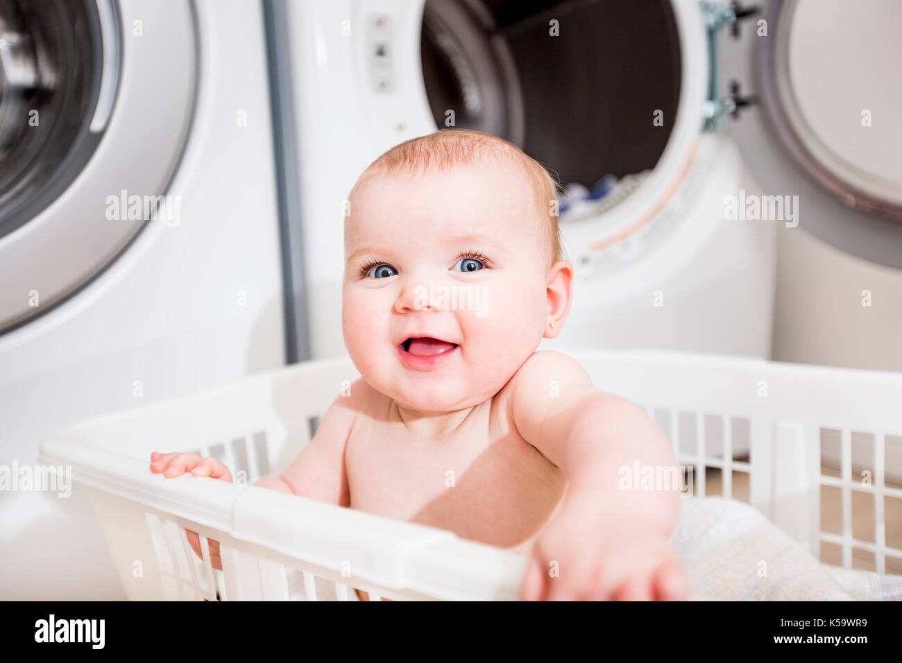 Portrait of an adorable baby sitting in a laundry basket Stock Photo