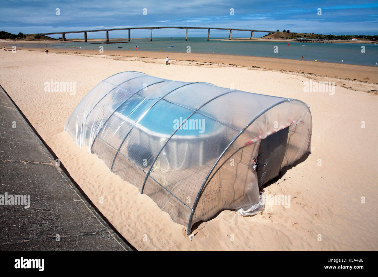 Very small indoor swimming pool on the beach of Fromentine in France. The bridge, pont of Noirmoutier, in the background Stock Photo