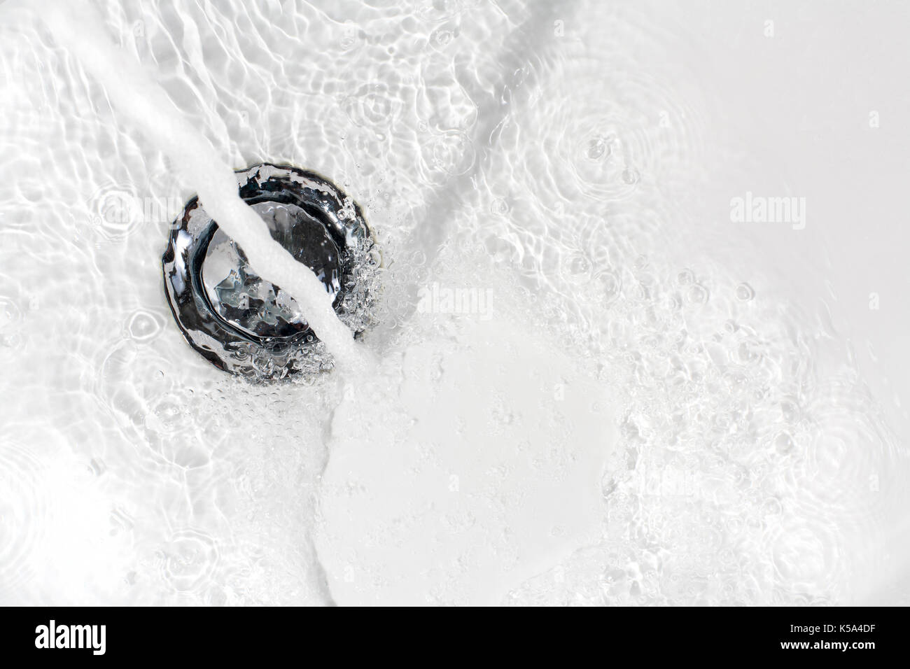 Fresh water running down the drain of a ceramic washbasin Stock Photo