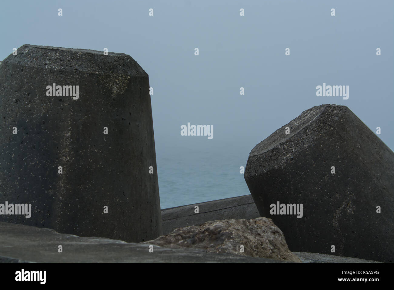 cement structure and rocks for stopping the sea in a pier in a foggy ...
