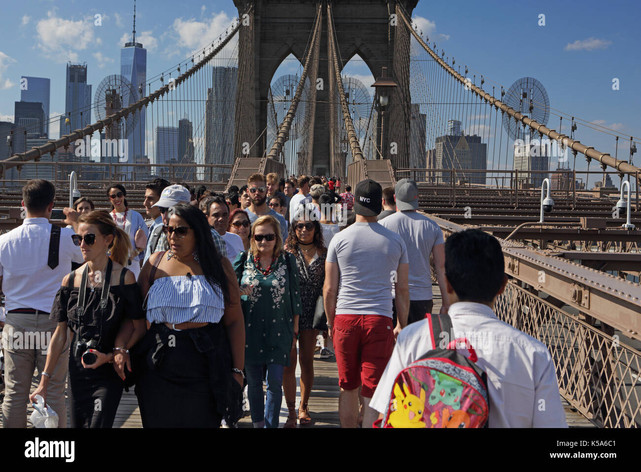 Crowds of tourists walk over Brooklyn Bridge on a sunny Labor Day holiday with Lower Manhattan in the background Stock Photo