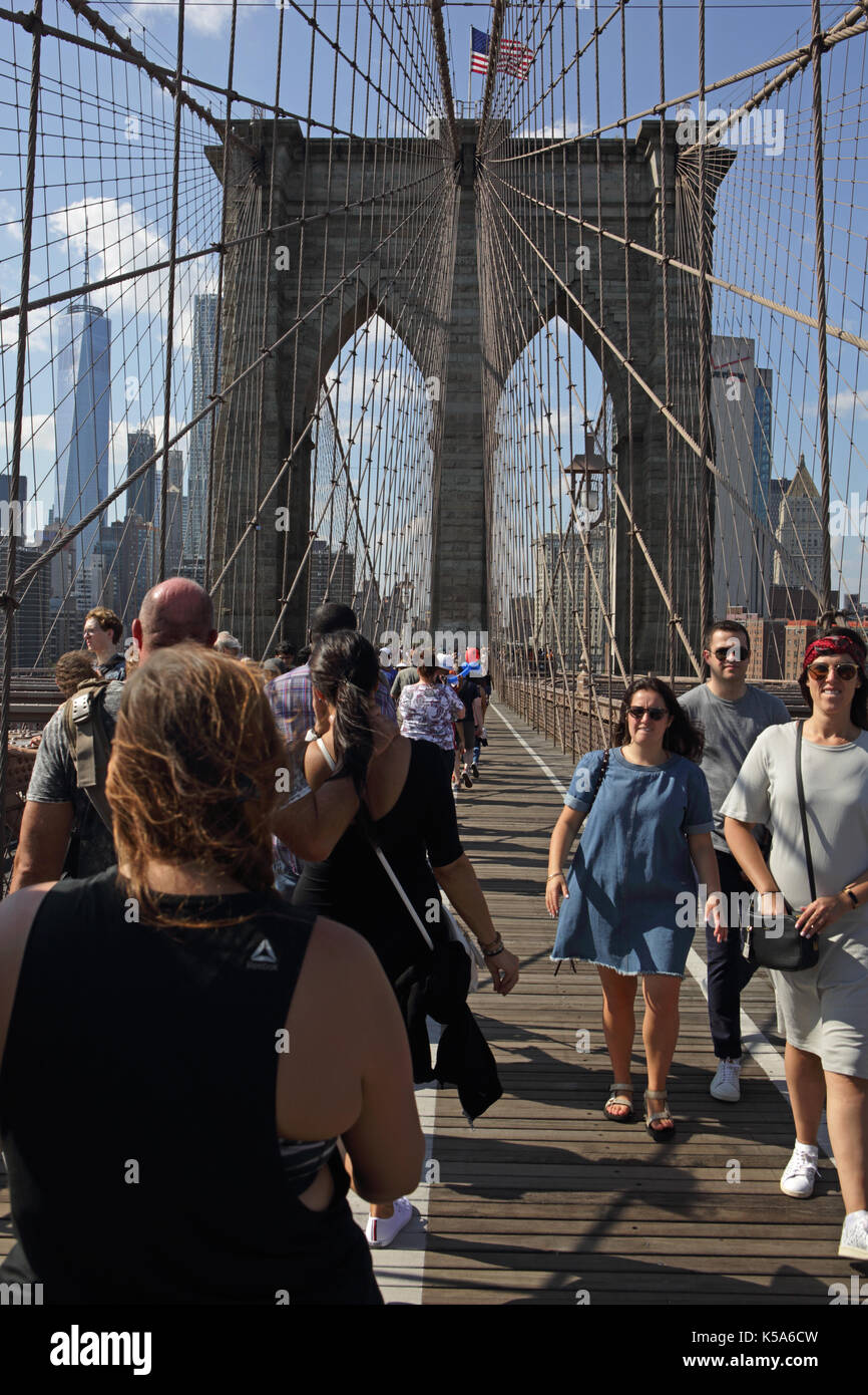 Crowds of tourists walk over Brooklyn Bridge on a sunny Labor Day holiday with Lower Manhattan in the background Stock Photo