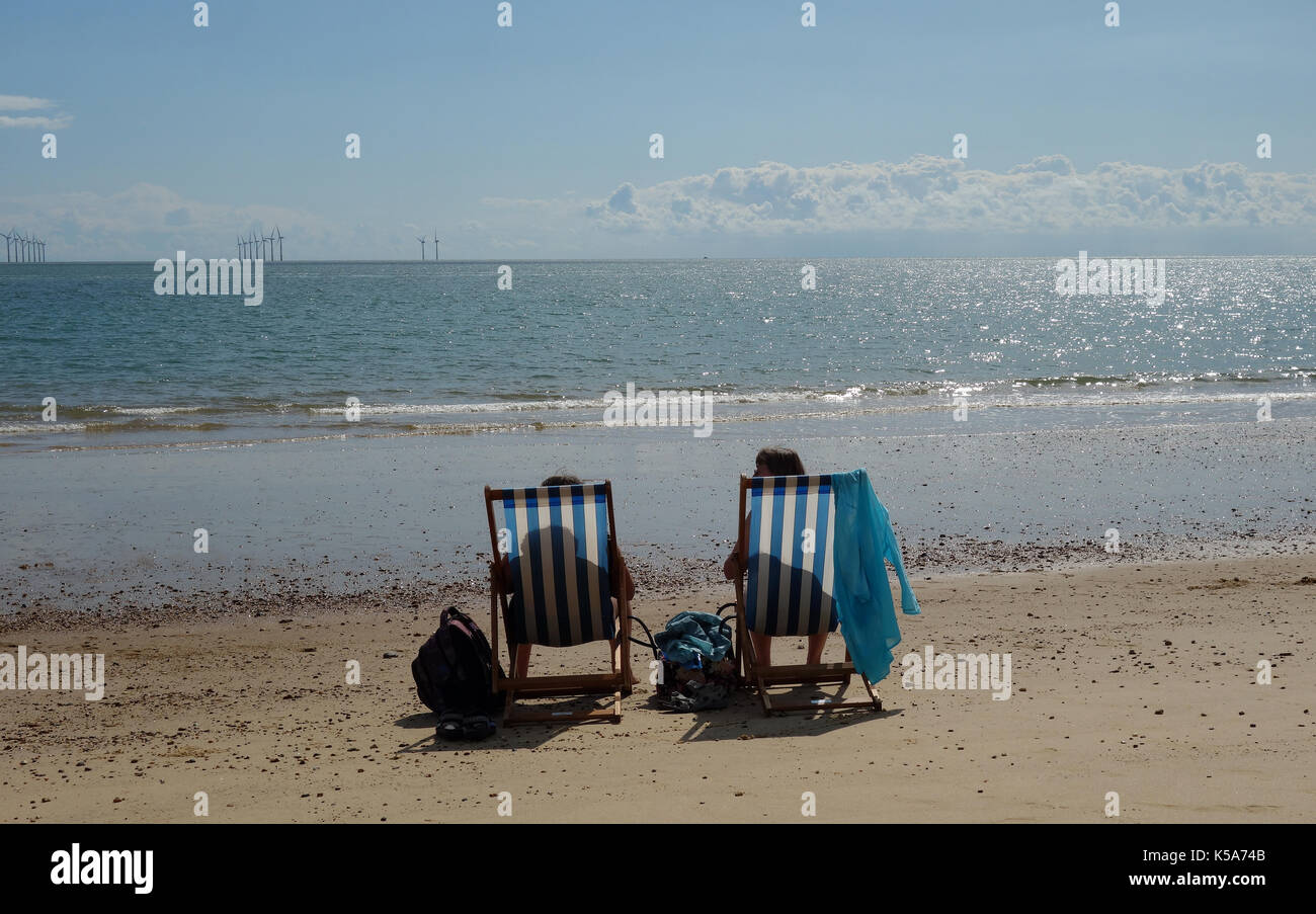 Women sitting in deck chairs on Clacton-on-Sea beach Stock Photo