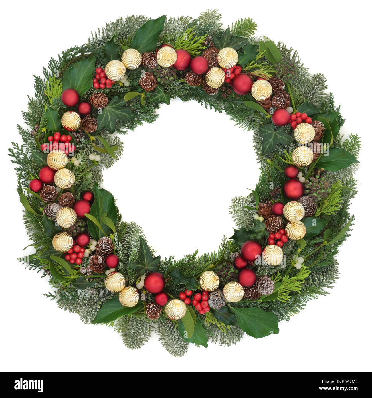 Christmas wreath decoration with red and gold bauble decorations, mistletoe, snow covered natural juniper fir, blue spruce, cedar, pine cones and ivy  Stock Photo