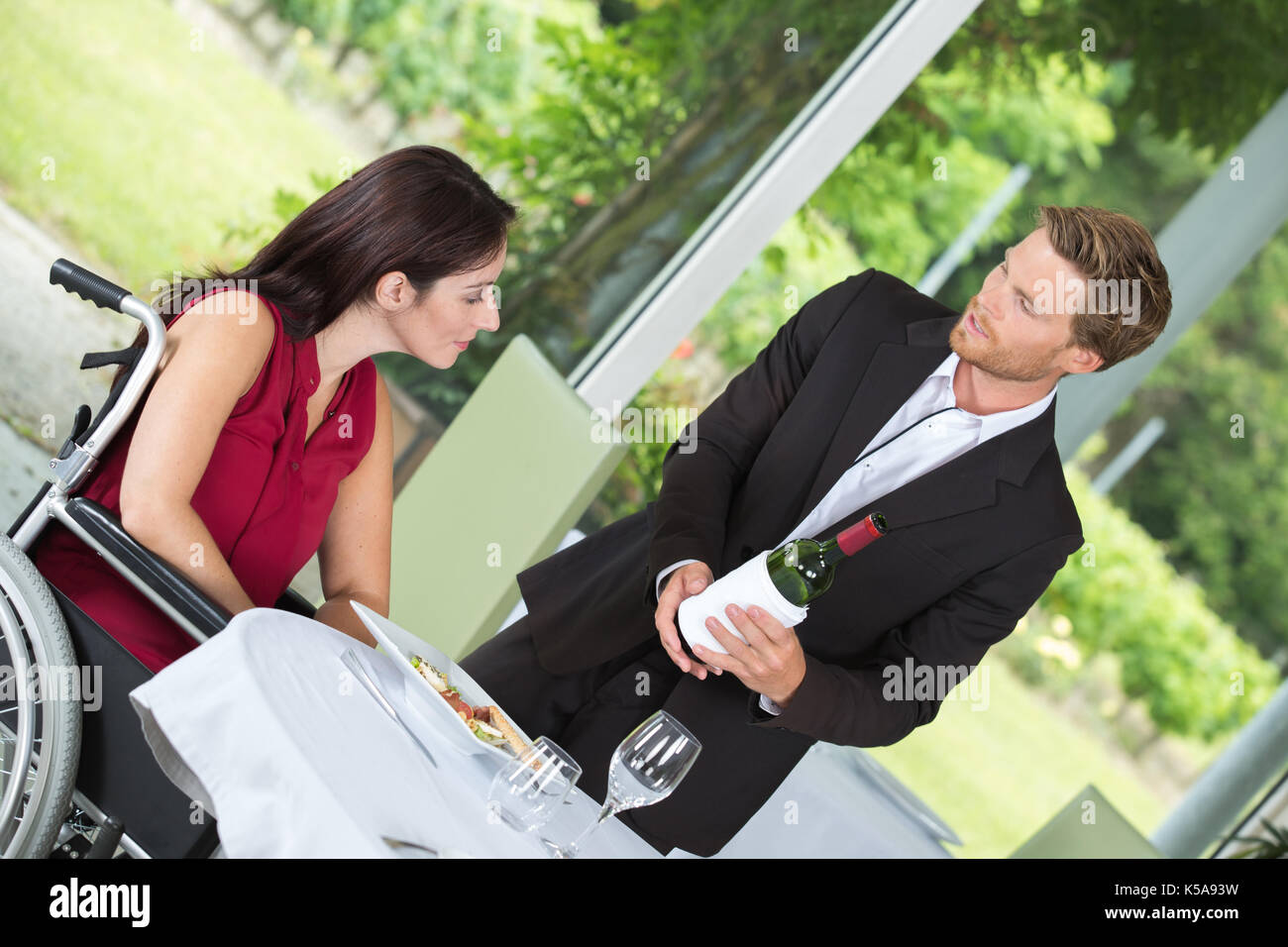 positive waiter bringing order to happy handicaped client Stock Photo