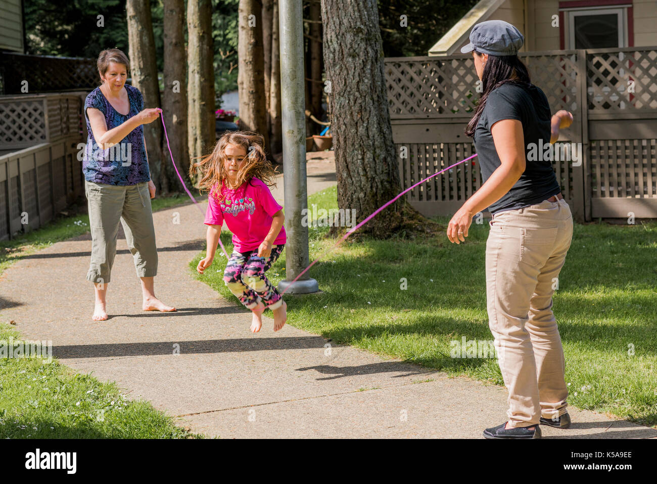Young girl playing skipping rope game with adults Stock Photo Alamy