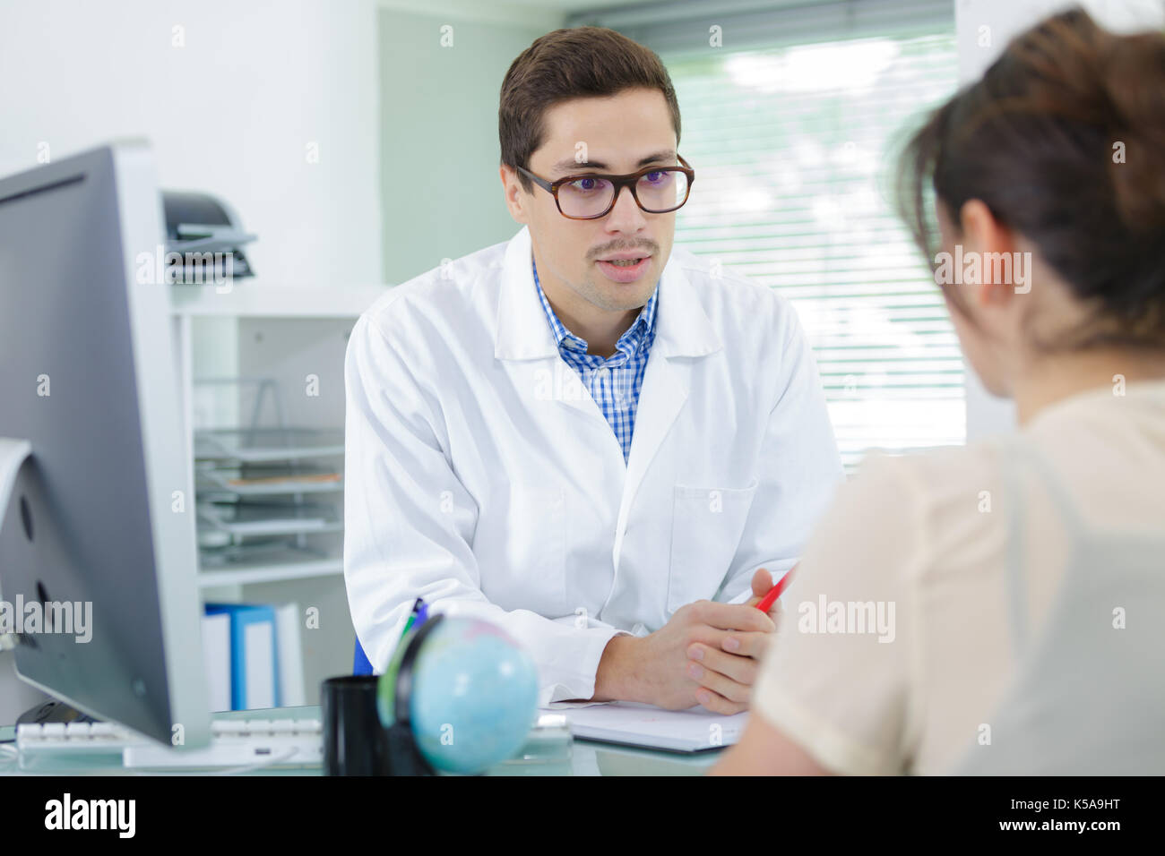 young doctor is talking to his female patient Stock Photo - Alamy