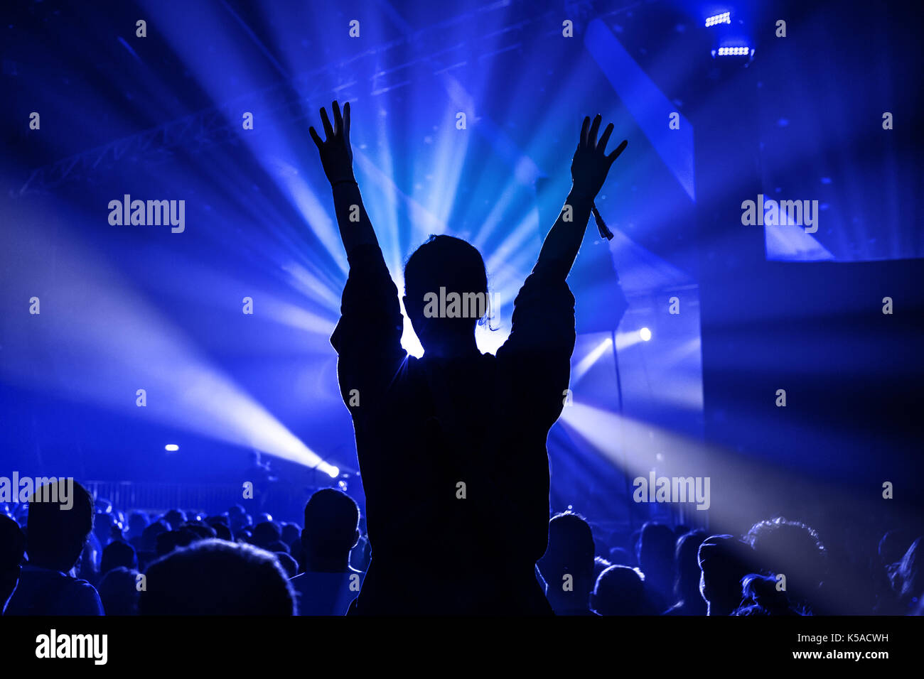 Silhouette of a Woman Dancing Whilst Sat On Someones Shoulders at a Music Concert Stock Photo