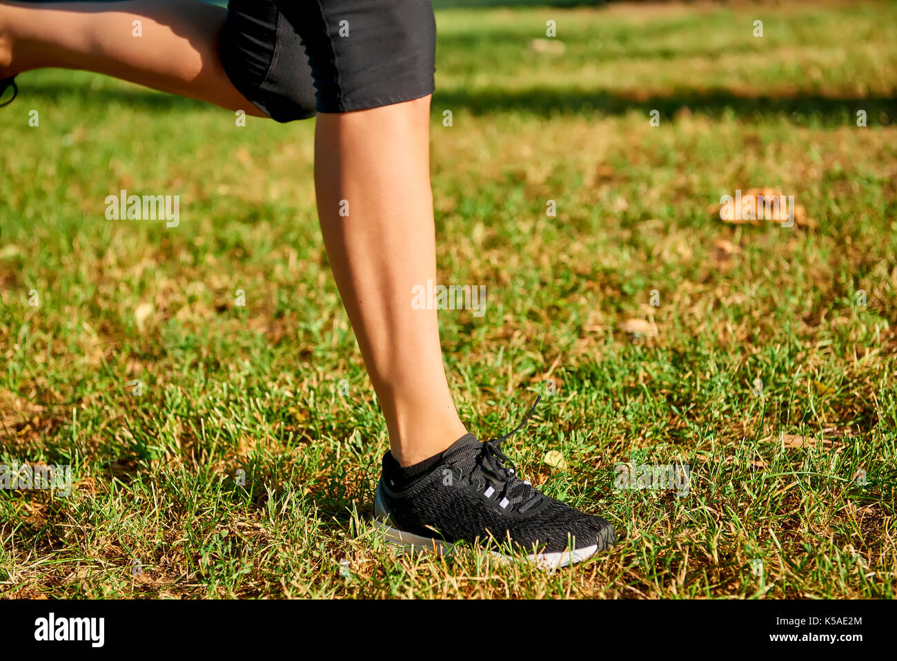 Close up of the legs of a young woman who is running off road in a park