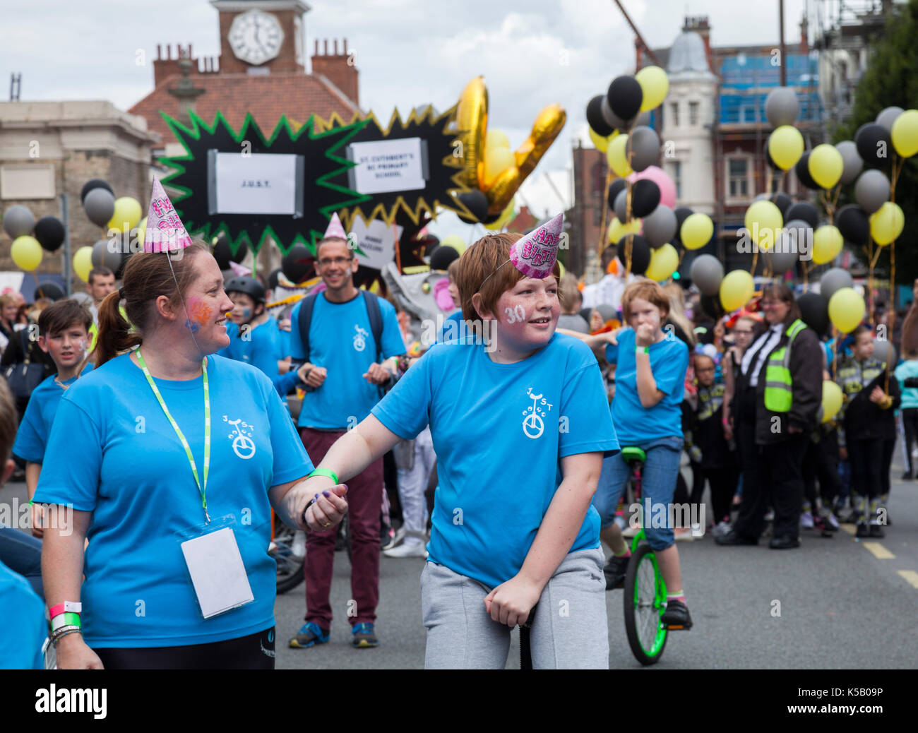 Children riding unicycles in the parade down the High Street at the