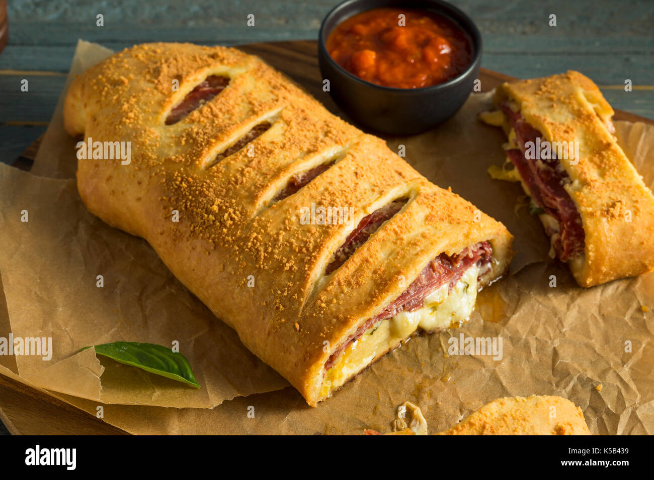 Homemade Cheesy and Meaty Italian Stromboli with Marinara Sauce Stock Photo