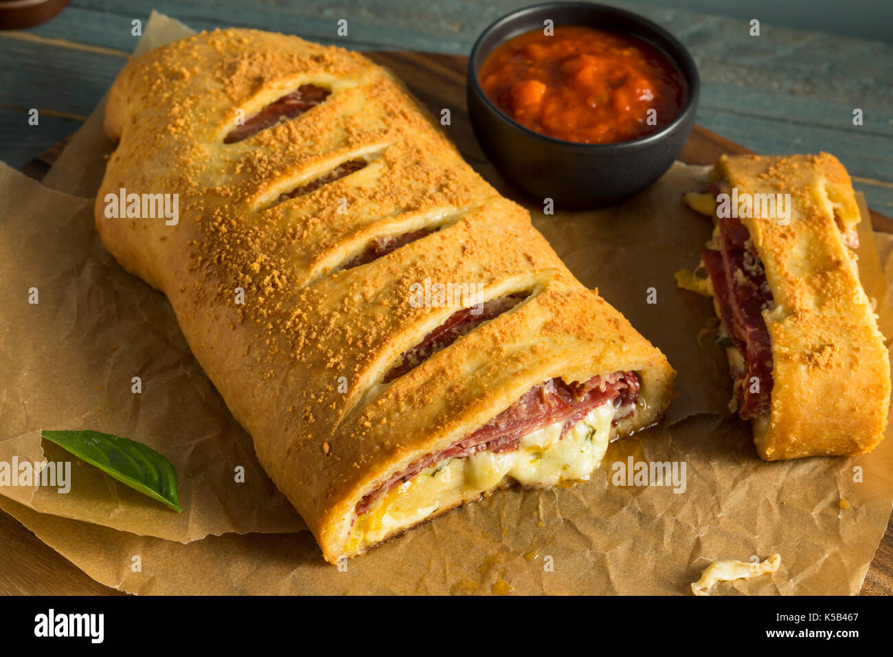 Homemade Cheesy and Meaty Italian Stromboli with Marinara Sauce Stock Photo