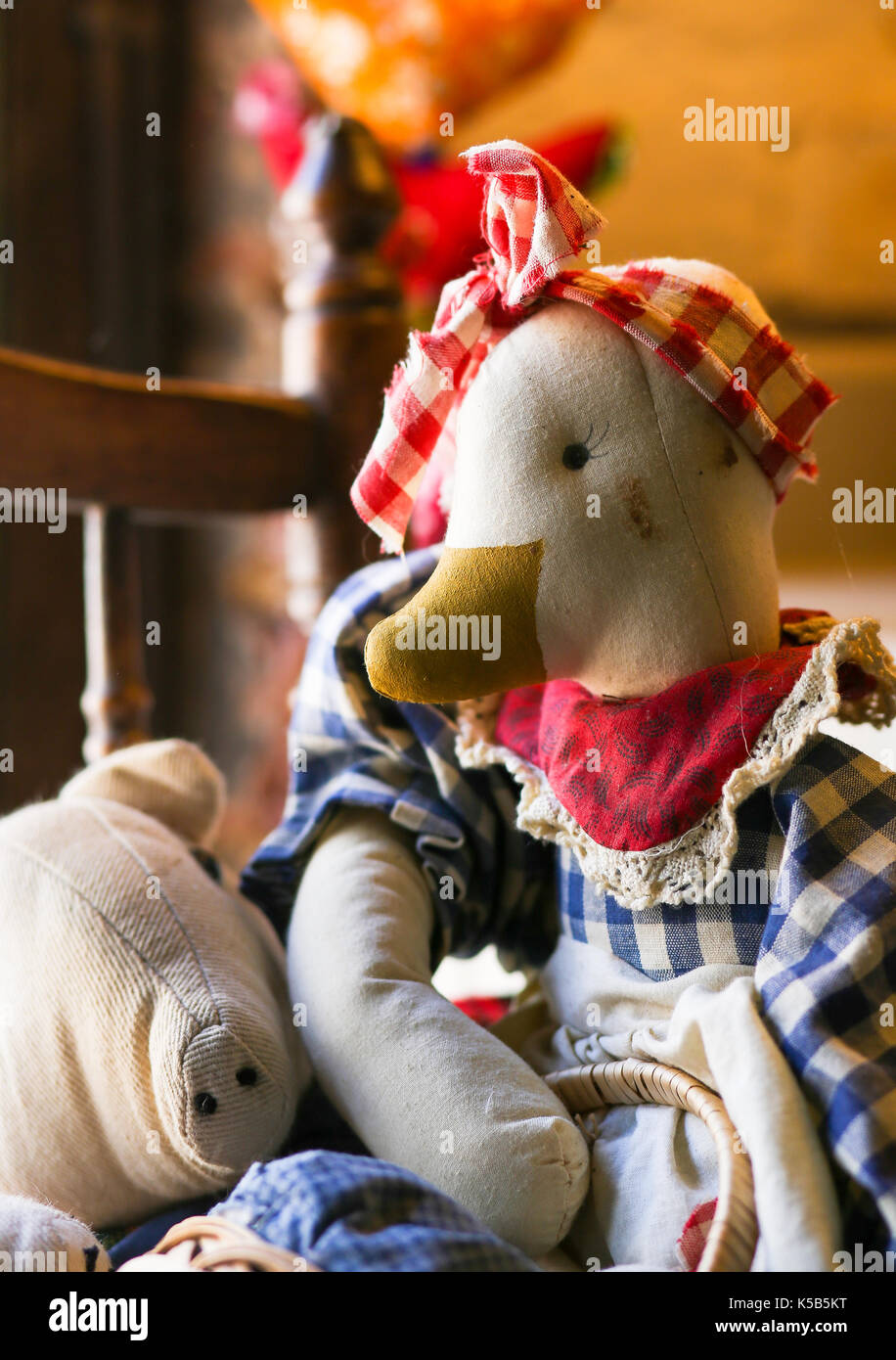 Cute old vintage duck fabric doll on the chair by the window with gingham cotton cloth Stock Photo