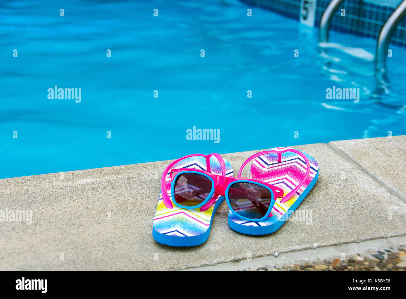 sunglasses and flip-flops by swimming pool Stock Photo - Alamy