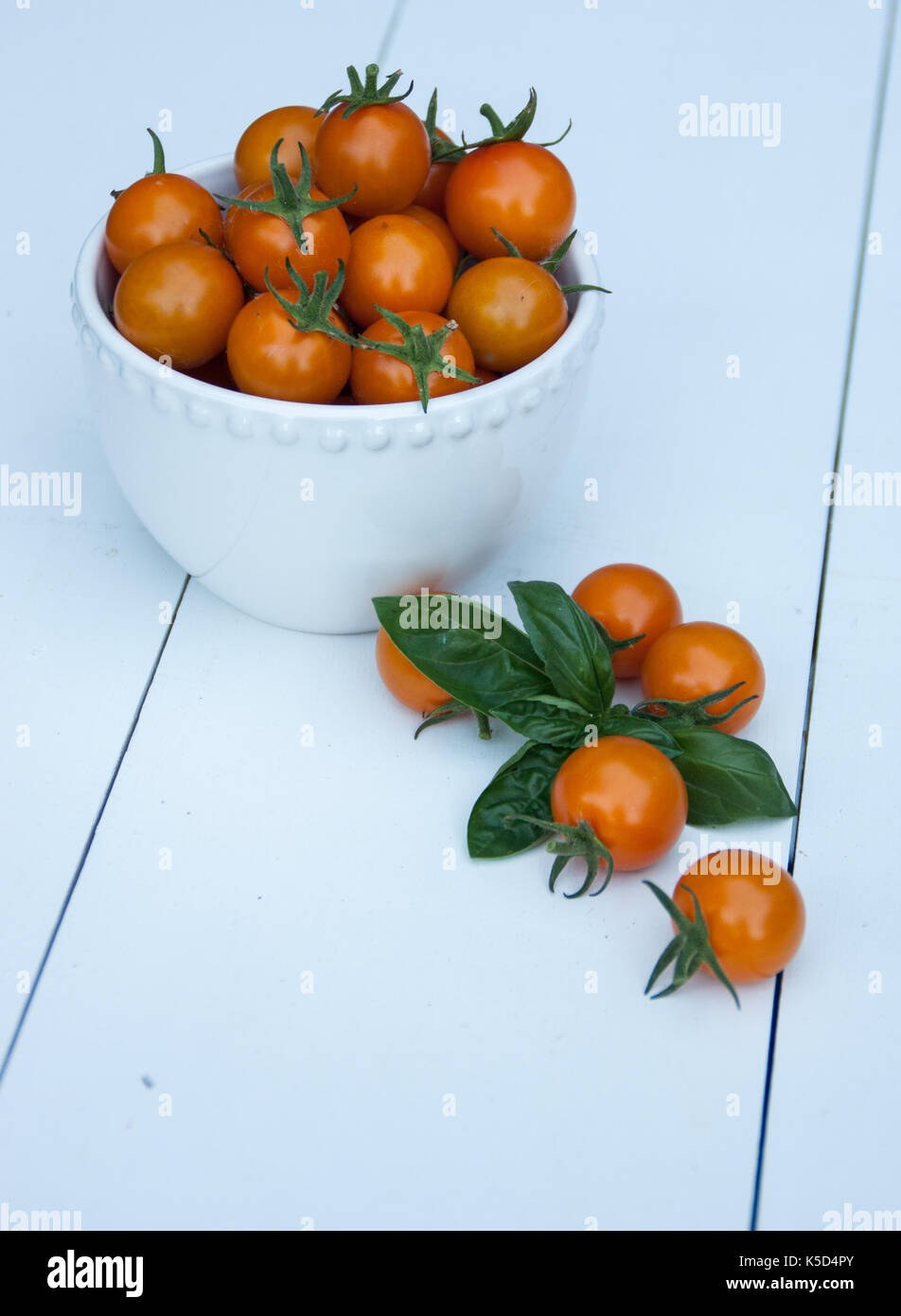 Sun Gold Cherry Tomatoes, in a white bowl, on a white background. Stock Photo