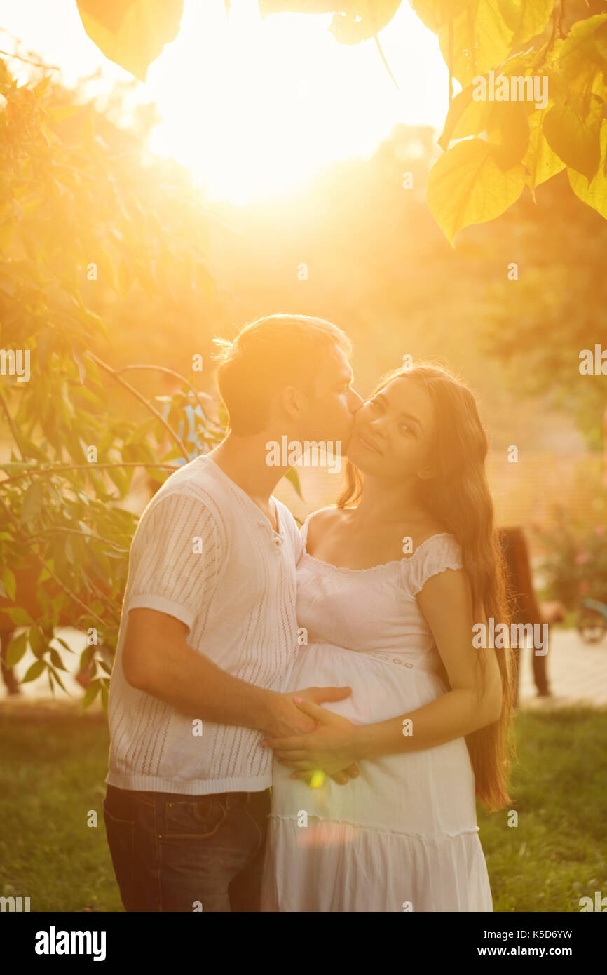 Family. A pregnant wife and husband. He kisses her on the cheek. Family ...