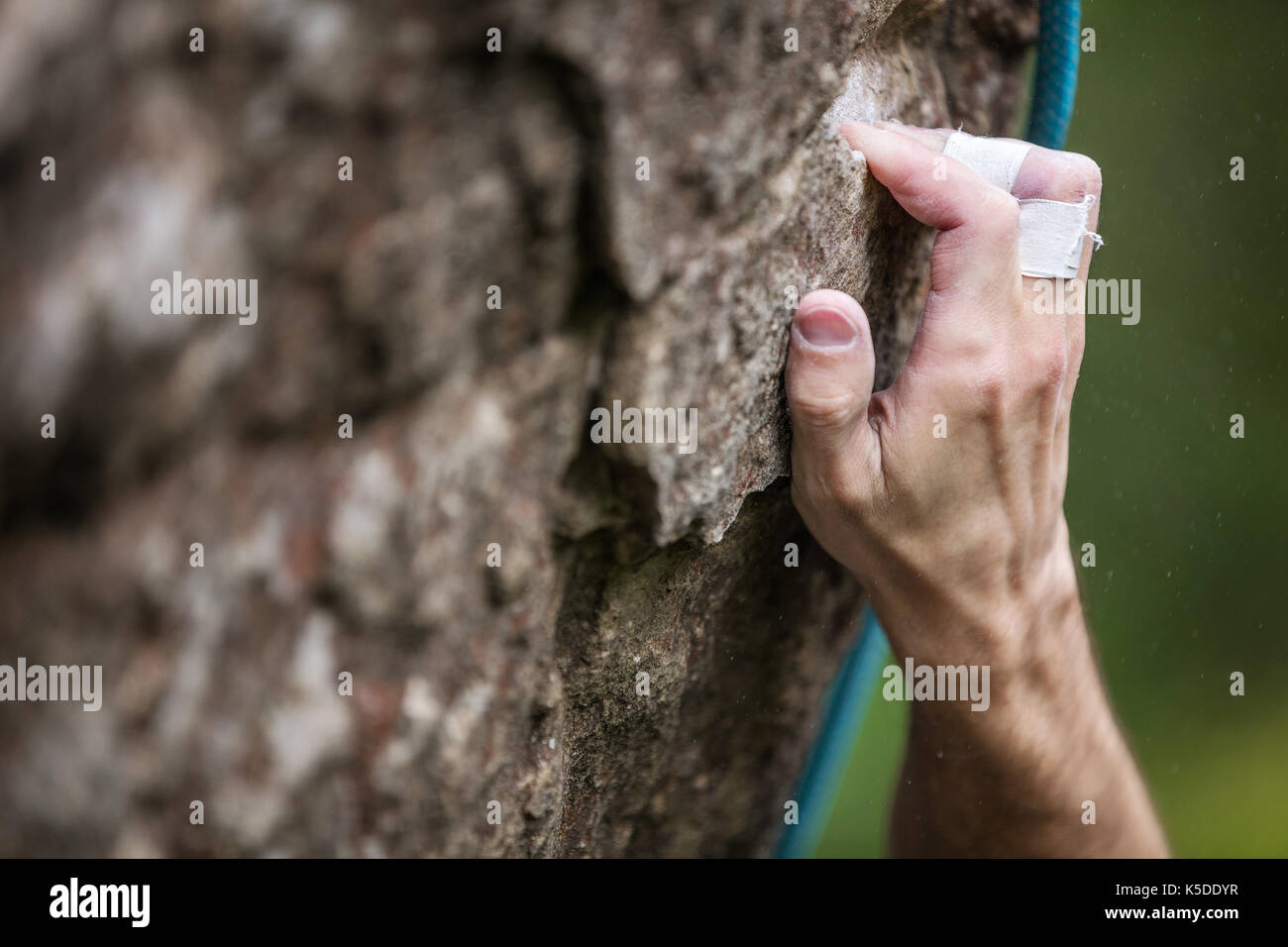 Closeup view of rock climber's hand gripping hold on natural cliff Stock Photo