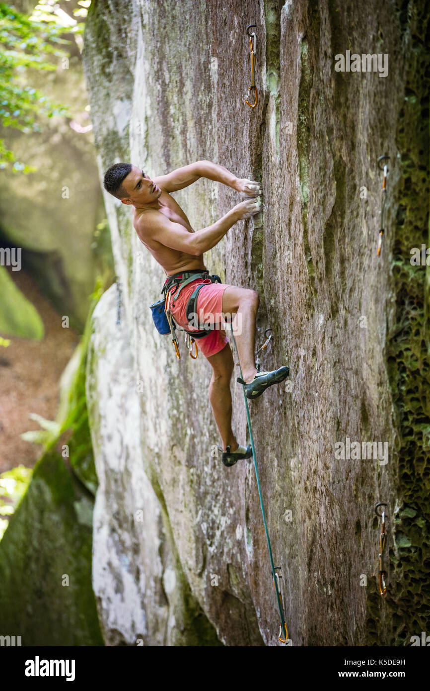 Young male rock climber on challenging route on vertical cliff Stock Photo